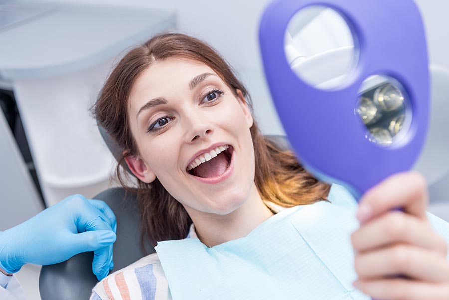 woman looking at teeth after teeth whitening in Seattle